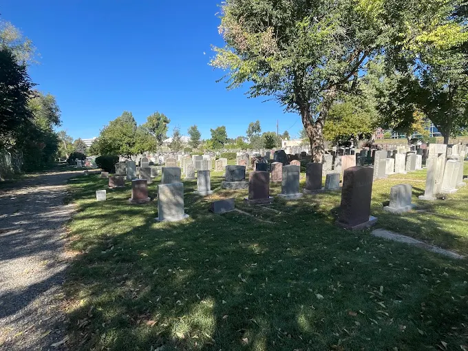 Gravel path leading past headstones and shade trees on the grounds of Golden Hill Cemetery